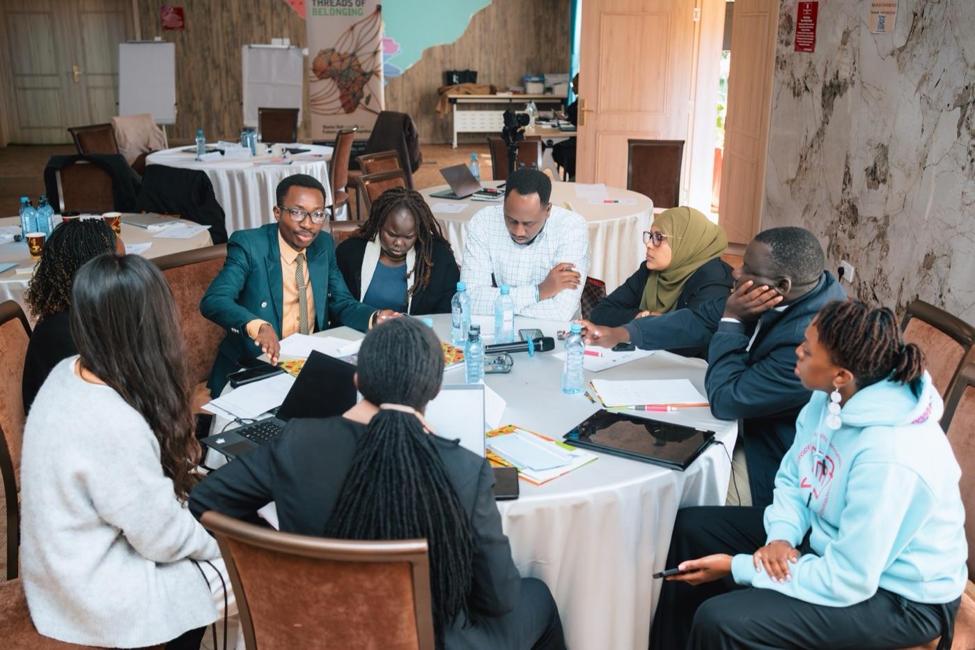 Refugee experts around a round table at R-SEAT's 2026 workshop in Kenya, working through a draft together