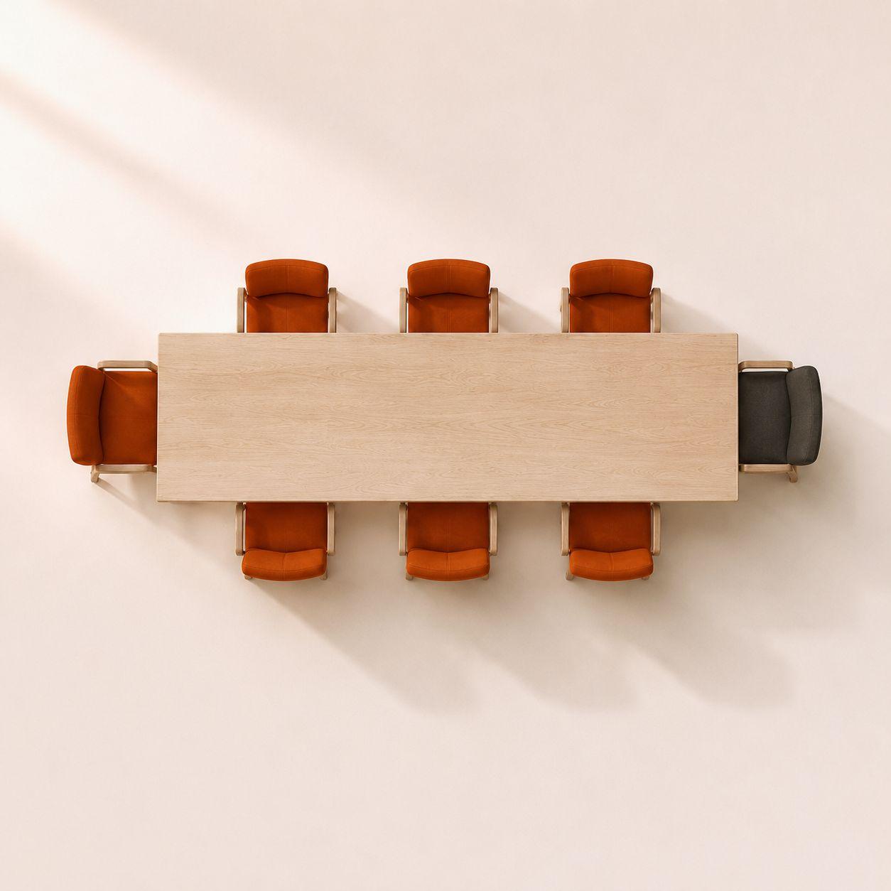 A long table seen from above, orange chairs along both sides, one pulled up at the head